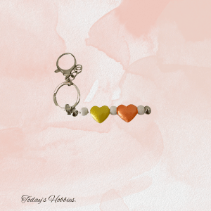 Handcrafted bangle and bead accessories featuring a keychain with heart-shaped beads in yellow and orange
